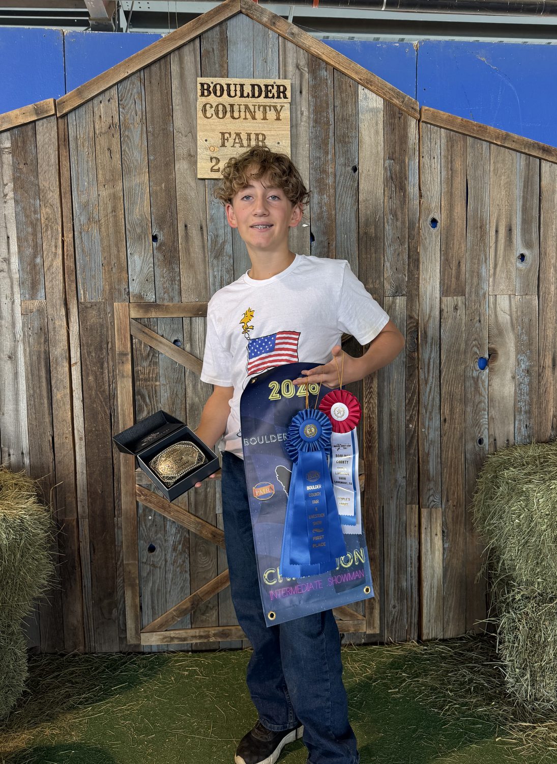 Colin holding his Grand Champion banner, first place rosette, ribbons and
           belt buckle at the Boulder County Fair 2026